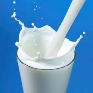pouring milk in a glass isolated against white background